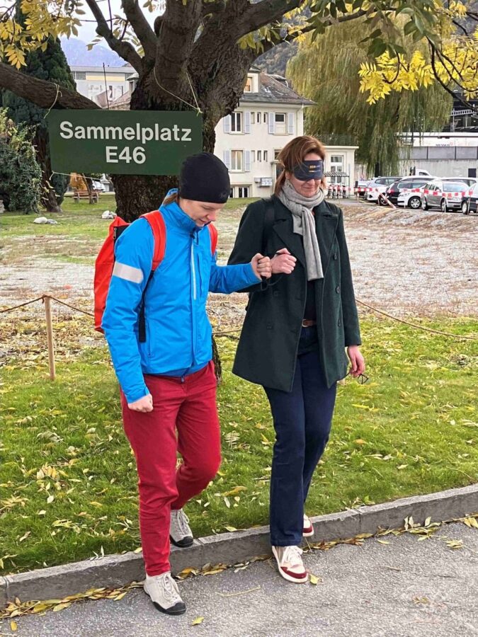 Ein Guide des Vereins blind-jogging leitet eine Person unter der Dunkelbrille über einen Randstein
