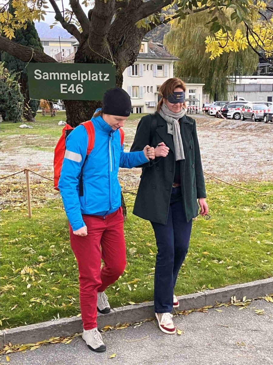 Ein Guide des Vereins blind-jogging leitet eine Person unter der Dunkelbrille über einen Randstein