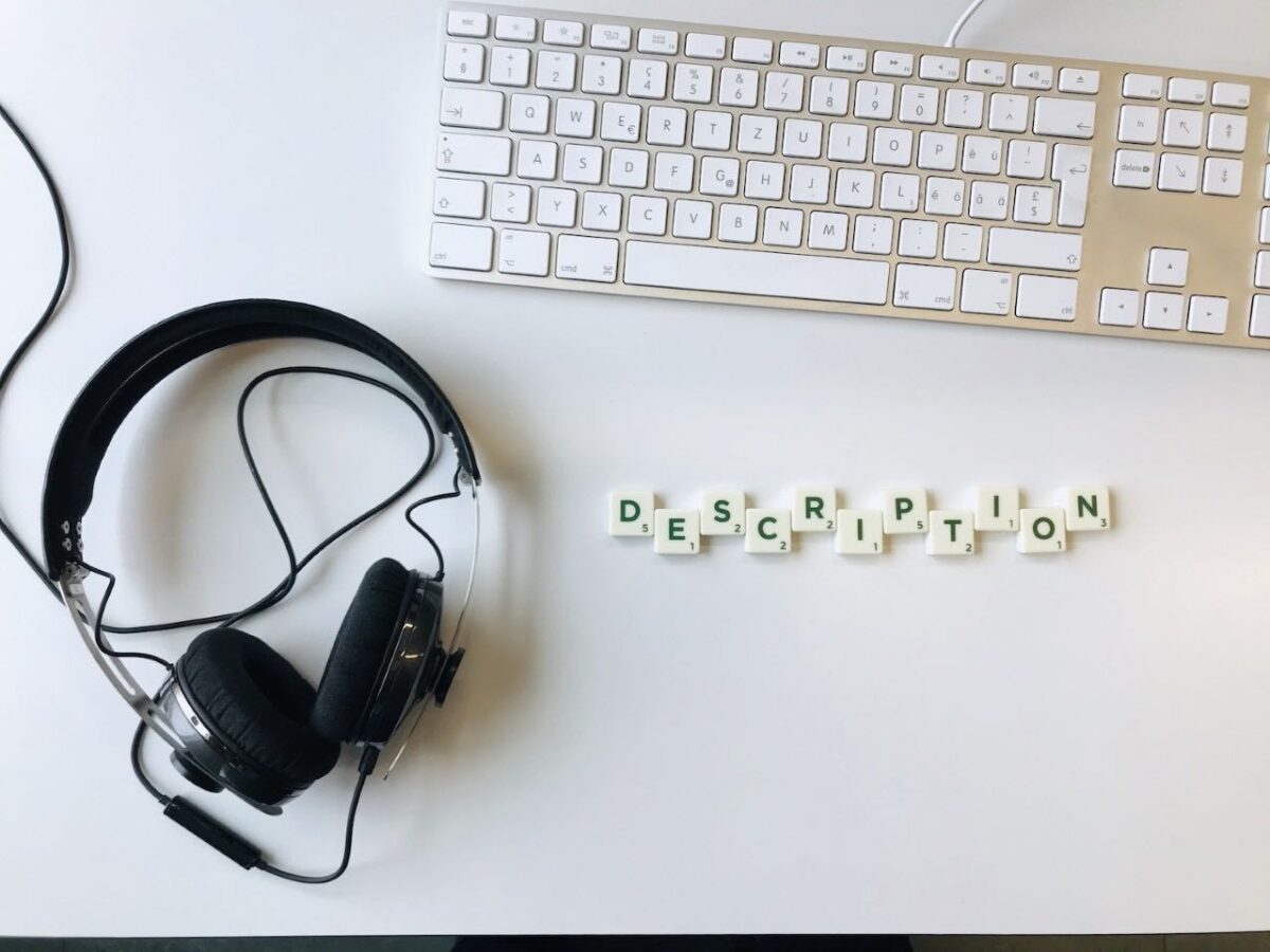 Wir sehen einen Kopfhörer und eine Tastatur, daneben liegen Buchtaben zum Wort "Description" geformt.