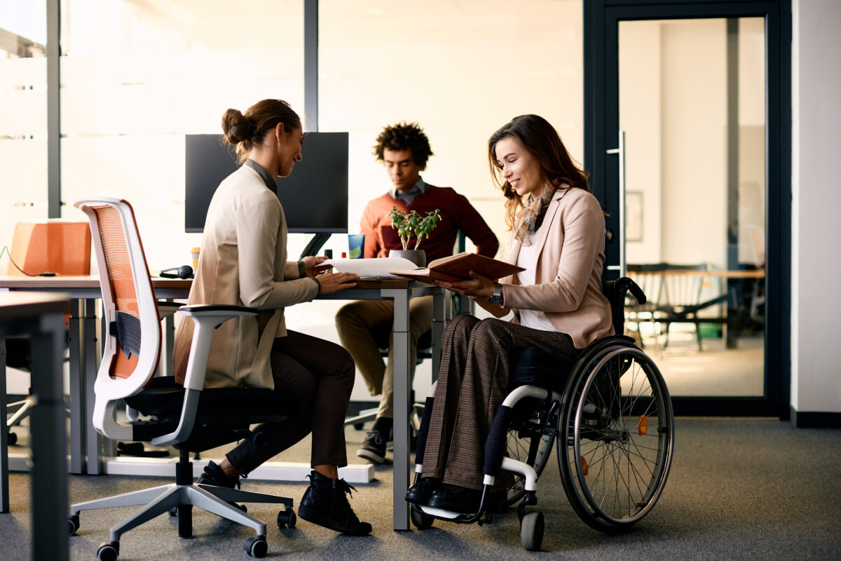 3 Personen bei einer Projektbesprechung an einem Bürotisch.