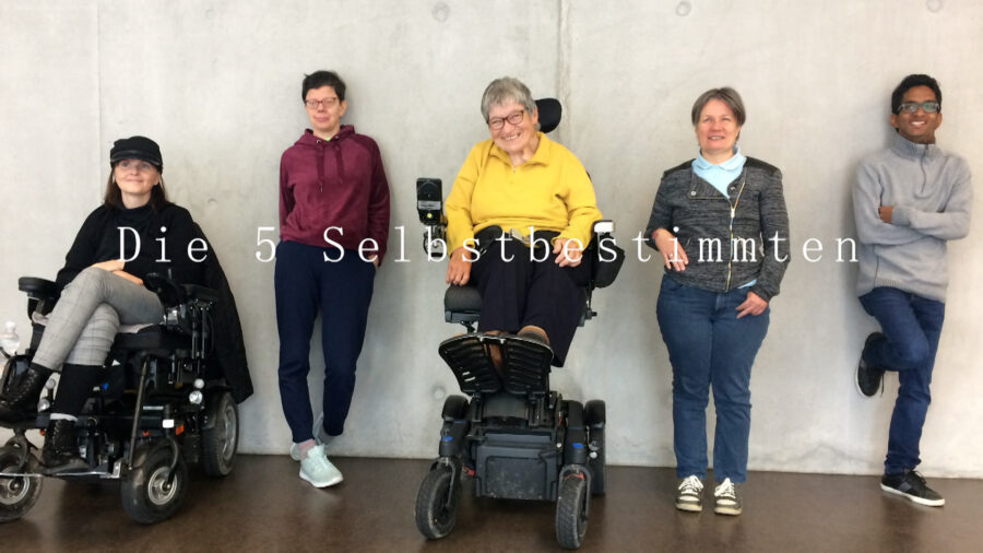 5 Personen, davon 2 im Rollstuhl sind lachen nebeneinander aufgereiht.
