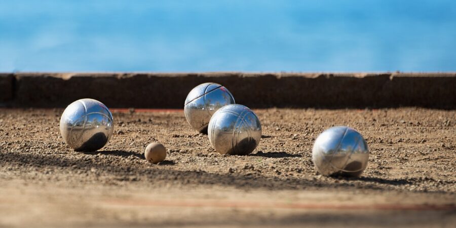 Petanque Kugeln liegen um die Zielkugel. Die Zielkugel ist eine kleine Kugel. Das Ziel der Mannschaft ist es, ihre Kugeln so nah wie möglich an die Zielkugel zu werfen.