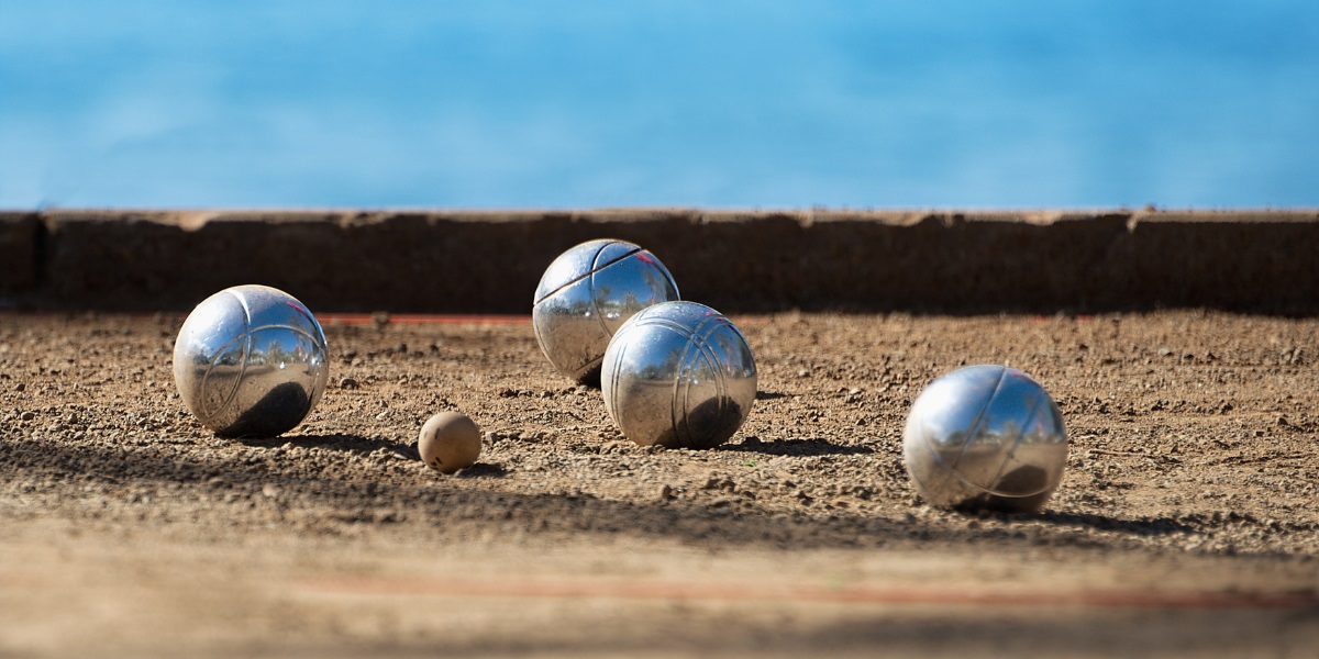 Petanque Kugeln liegen um die Zielkugel. Die Zielkugel ist eine kleine Kugel. Das Ziel der Mannschaft ist es, ihre Kugeln so nah wie möglich an die Zielkugel zu werfen.