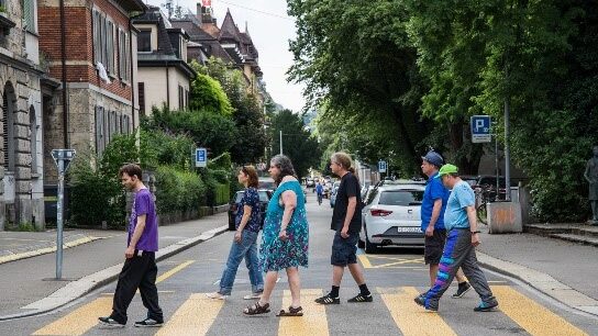 Fünf Menschen gehen über einen Zebrastreifen.