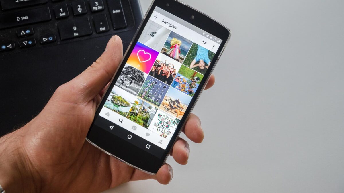 Eine Person hält ein Handy in der Hand und ist gerade auf einen social Media Kanal.