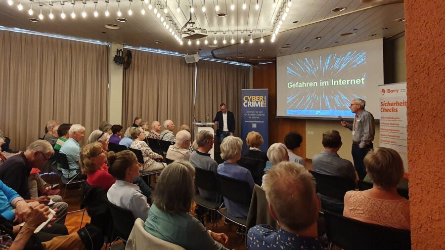 Mehrere Menschen schauen auf eine Präsentation. Die Präsentation trägt den Titel "Gefahren im Internet".