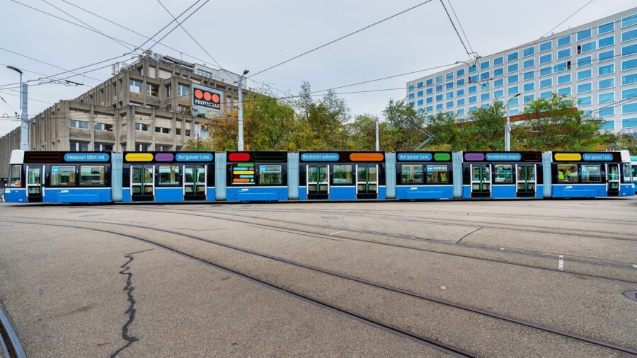 Die Seitenansicht eines Niederflur-Tram zeigt eine durchgehende Beschriftung oberhalb der Fenster. Der Text lautet: "Inklusion fährt mit. Auf ganzer Linie. Rücksicht nehmen. Auf ganzer Linie. Verständnis zeigen. Auf ganzer Linie."