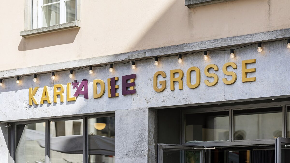 Ein Ausschnitt der Fassade des Debattierhauses. In der Mitte steht «Karl der Grosse» in goldener Farbe. Einige Buchstaben werden durch violette Buchstaben ergänzt oder überklebt. So heisst es «Karla die Grosse».